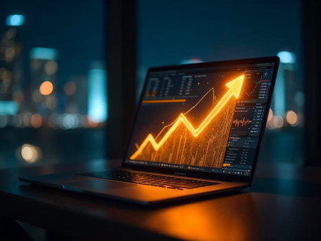 Laptop screen displaying glowing upward financial chart with city lights in backgroundの素材