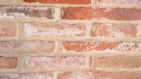 Detailed view of an old brick wall with rough mortar and aged red tones