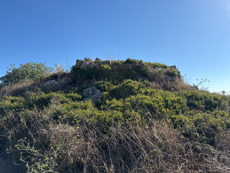 Archaeological remains of ancient Nuraghe stone tower surrounded by rural Sardinian landscape