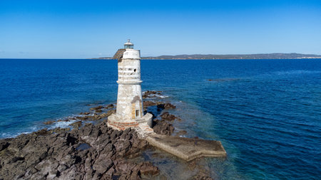 Aerial view of the historic Mangiabarche Lighthouse surrounded by turquoise sea and rocky coastの写真素材