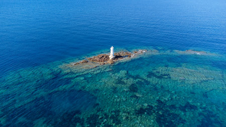 Aerial view of the historic Mangiabarche Lighthouse surrounded by turquoise sea and rocky coastの写真素材