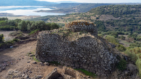 View of the Nuraghe Iloi archaeological site in Sedilo, Sardinia, featuring ancient basalt stone walls and panoramic landscapeの写真素材