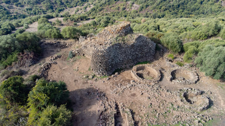 View of the Nuraghe Iloi archaeological site in Sedilo, Sardinia, featuring ancient basalt stone walls and panoramic landscapeの写真素材