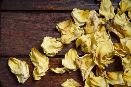 Yellow dried rose petals on wooden boards brown colorの写真素材