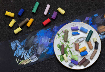 artist's hands with colored pastel crayons on a black backgroundの写真素材