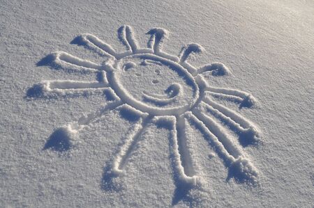 Smiling sun shape drawn on white snow surfaceの写真素材