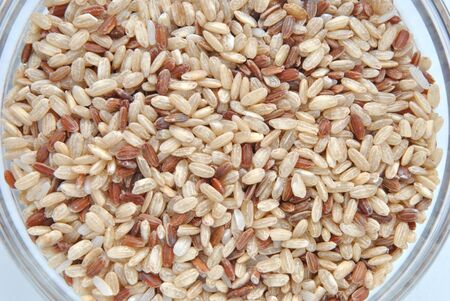 Macro shot of integral, brown rice in a glass bowl on white background の写真素材