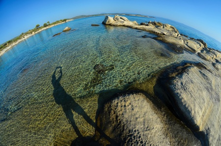 Seascape fisheye view with a huge stones and shadow of photographer in morning sunlight, Carydi beach, Chalkidiki, Sithonia, Greeceの写真素材