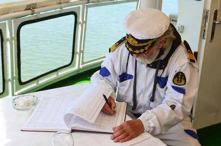 Old experienced captain fills the logbook after the ship navigation