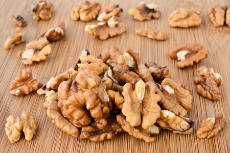 Pile of shelled walnuts on wooden chopping board, macro shot
