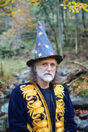 Portrait of old mysterious wizard having a rest in deep autumn forestの写真素材