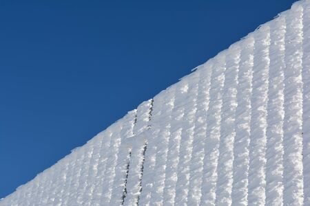 Abstract background, clear blue sky and iron fence completely covered by hoarfrost, diagonal patternの写真素材