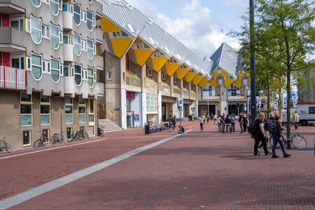 A view of the characteristic yellow cube houses in the center of Rotterdam, the Netherlands and tourists in the square in front of the houses.のeditorial素材