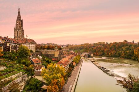 Romantic coloured sunset sky with colourful autumn foliage and historical buildings along the banks of the river Aare in the old city center of Bern, Switzerlandの写真素材