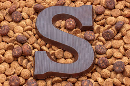 A chocolate letter S on a pile of dutch candy called Pepernoten, traditional sweets for the...