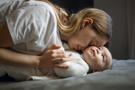 Happy woman looks at her baby and smiles. Beautiful baby smiles at mother. Mother with her own baby.の写真素材