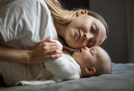 Beautiful mother with her baby. Young beautiful woman looks at her little daughter. Baby girl laughing in her mothers arms.の写真素材