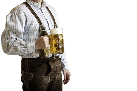 Bavarian man dressed with original leather trousers holds an Oktoberfest beer stein into the cameraの写真素材