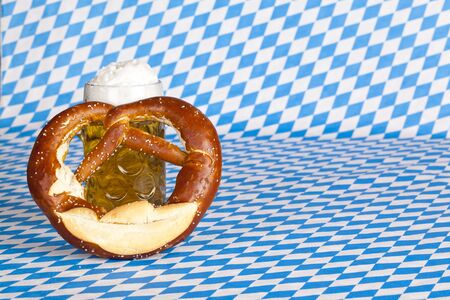 Oktoberfest beer stein with pretzel and Bavarian flag in background.の写真素材
