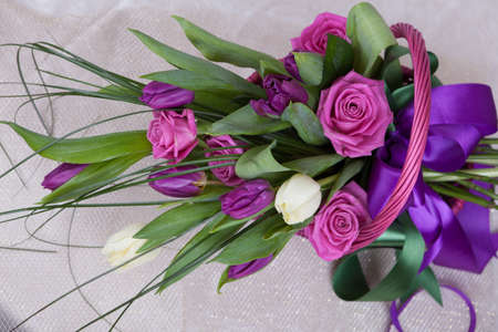 Bouquet of pink roses, white and purple tulips in a basket compositionの写真素材
