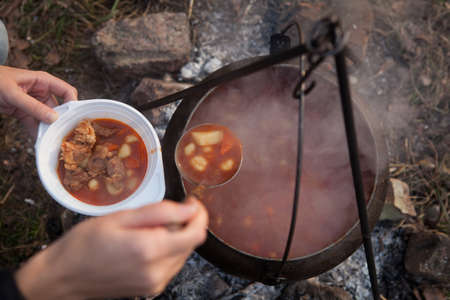 Cooking bogracs gulyas soup in a cauldron on fire in forestの写真素材