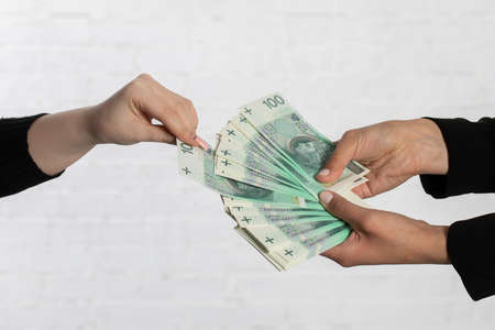 Spread-out fan-shaped paper banknotes hold young woman's hands.