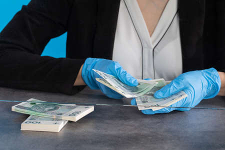 During an ongoing epidemic of infectious disease, the cashier gives cash in protective gloves.の写真素材