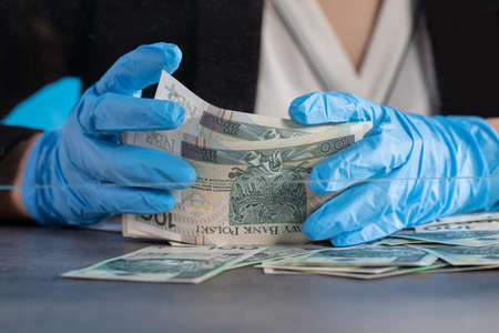 During an ongoing epidemic of infectious disease, the cashier gives cash in protective gloves.