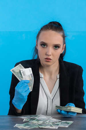 The cashier has randomly distributed banknotes on the desk behind the glass and tries to count them all exactly.の写真素材