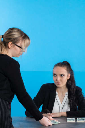At a bank position, an employee accepts large sums of money from a young woman.