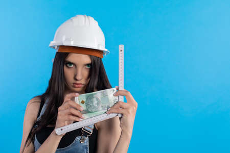 A woman in a hard hat holds a bundle of banknotes in her hand and encourages cooperation.の写真素材