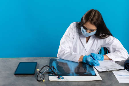 A young lady doctor in the office looks at the lungs and expects a good result.