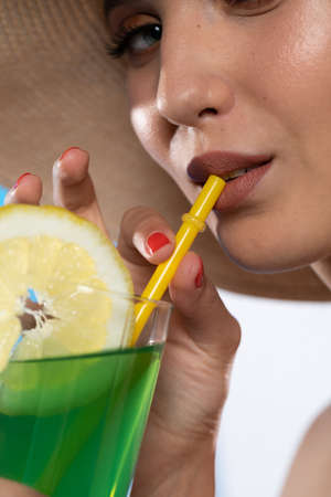 A teenager sipping a cold alcoholic drink through a straw during a hot summer.
