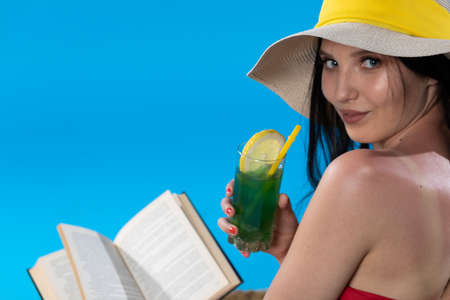 The teenager takes a sun bath and relax reading a romantic book and sipping a drink.の写真素材