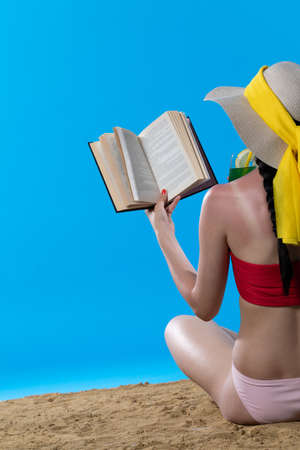 The teenager takes a sun bath and relax reading a romantic book and sipping a drink.の写真素材