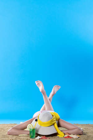 While sunbathing on the beach, a teenager drinks a cold alcoholic drink.の写真素材