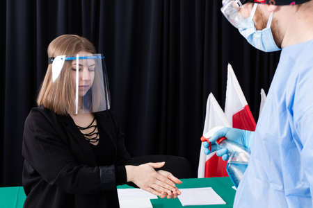 Hand disinfection. Hand splashes with liquid and alcohol. Protective helmet. Young Adult Woman.