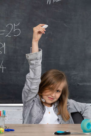 An urgent schoolgirl reports to the board to solve the task. Blackboard. A young girl with a smile...