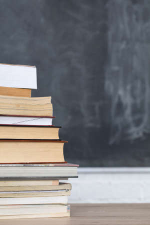 School readings. Stack of many books. A school board in the background is not thoroughly wiped with...