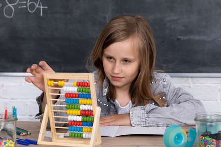 Abacus for adding different numbers. The girl at a math lesson adds on abacus. Old counting method.の写真素材