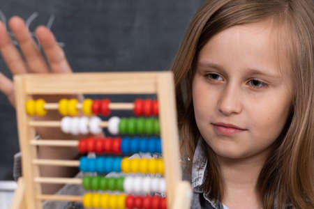 Abacus for adding different numbers. The girl at a math lesson adds on abacus. Old counting method.