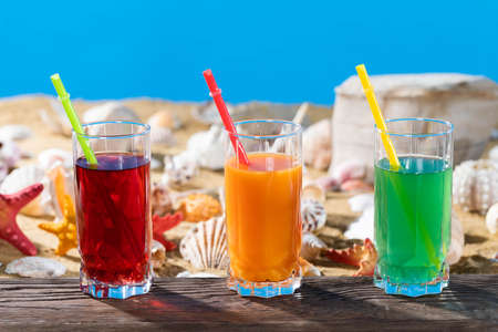 Fresh fruit juice in a tall glass. Shore of a sandy beach on a cool sea.の写真素材