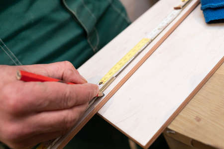 The builder measures the distance on the ceramic tile using a measuring tape. Distance measurement...