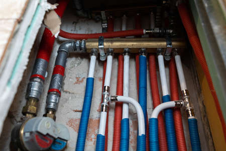 Plumbing installation in a newly designed bathroom. Water pipe in corrugated insulation in blue and red.の写真素材