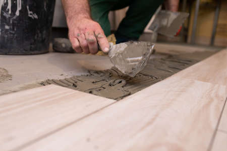 Professional construction worker laying ceramic tiles on the floor in the bathroom room.の写真素材
