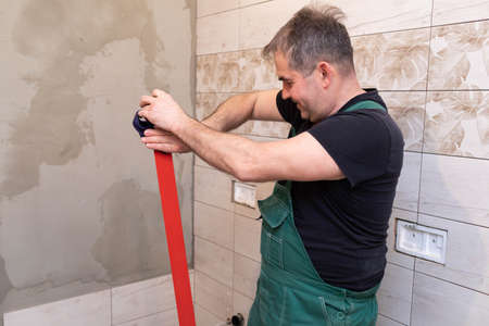 Red spirit level. Washes measuring tools with a wet cloth. Middle-aged manual worker. General construction worker.の写真素材