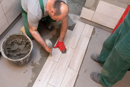 Rubber hammer. An experienced construction worker. Laying terracotta in the bathroom. Work clothes....