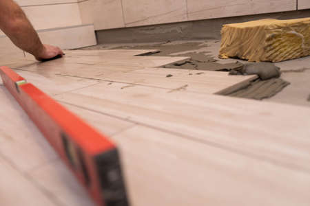 Cleaning the adhesive from ceramic tiles. Construction worker. Bathroom renovation work.の写真素材