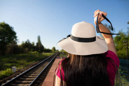 Sun hat with black bow. Summer train journey. Woman on the train platform.の写真素材