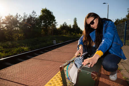 A young teenagers travel suitcase unfastened accidentally at a train station. Unlucky holiday at the train station.の写真素材